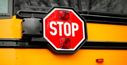 A yellow school bus parked with a visible stop sign on its side representing school transportation safety and the types of cases handled by a Concord bus accident lawyer.
