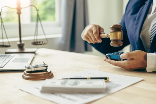 Car accident lawyer holding a gavel and car explaining to a victim the worth of their car accident claim.