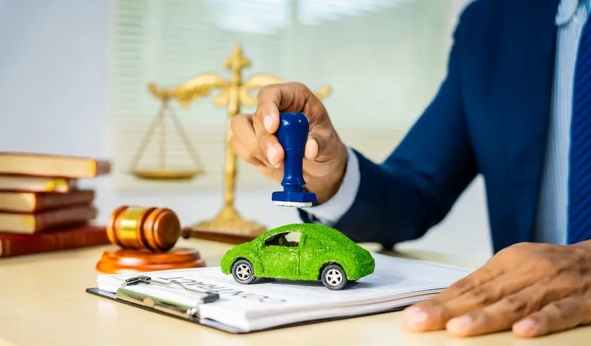 A legal professional is stamping documents with a green car model for car accident claims processing at Mogy Law in North Carolina.