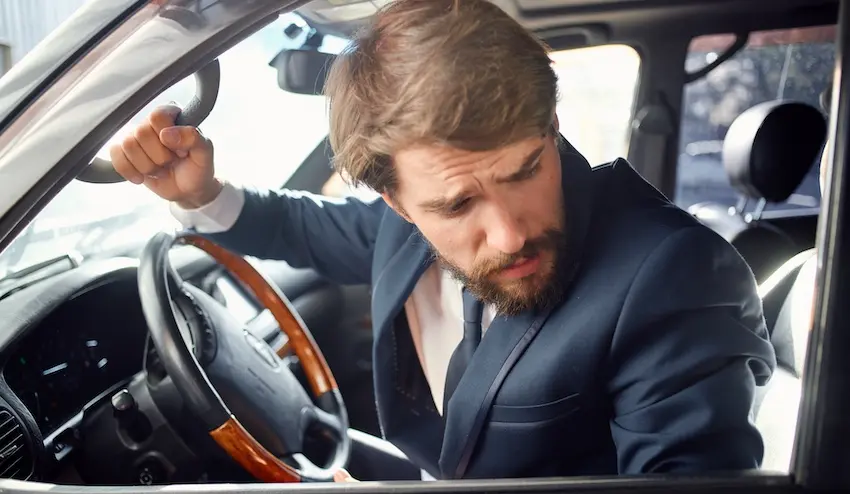 A distressed driver in a vehicle is experiencing pain after a collision requiring car accident claims assistance in North Carolina.