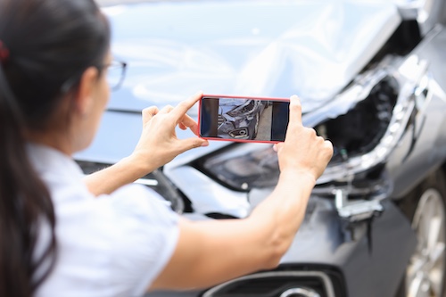 Woman Taking Photos Of Car Accident Damage